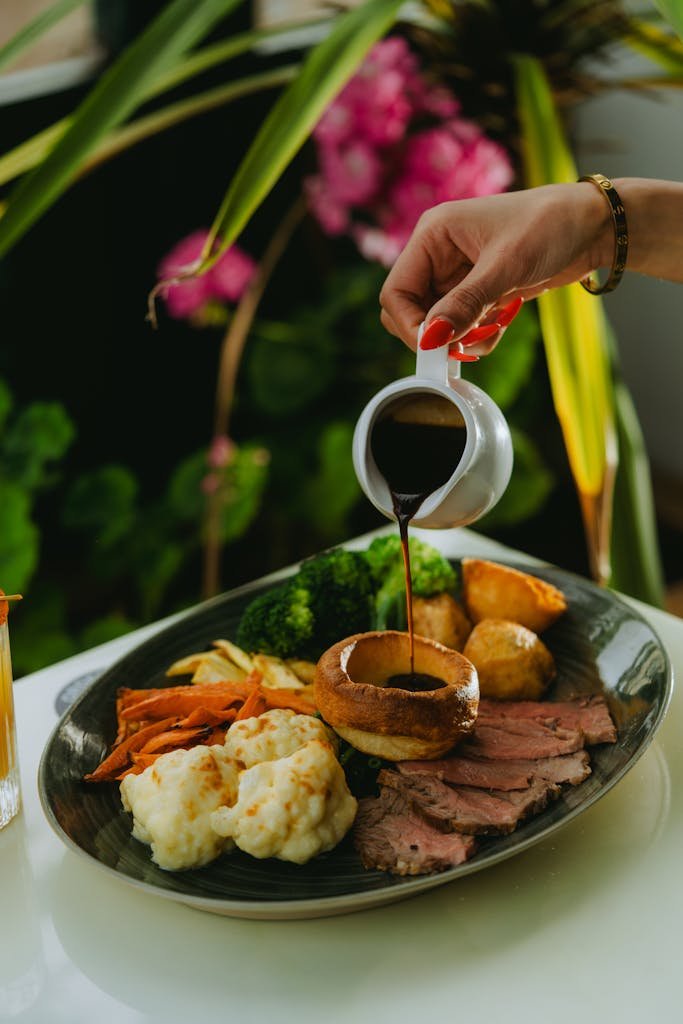A beautifully arranged roast dinner with vegetables, poured with gravy for a gourmet touch.