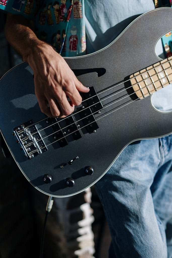 Musician performing with a sleek electric bass guitar in a home studio setting.